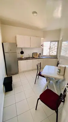 a kitchen with a table and two chairs and a table and a refrigerator at Modern & Sunny new appartement 2 rooms in Rabat centre - Hay Riad in Rabat