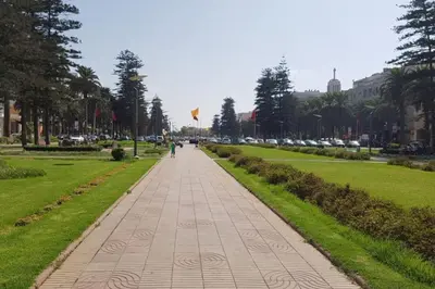 a person walking down a sidewalk in a park at Très bel appartement en face du parc, près du Novotel in Mohammedia