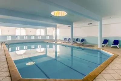 a large swimming pool with blue chairs in a building at Sea view Tamaris Dar Bouazza in Tamaris