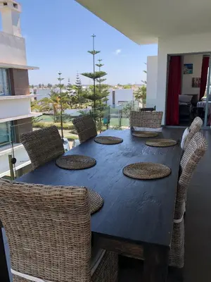 a dining room table and chairs with a view of the ocean at Eden Island Apartment with a View in Sidi el Haj Bou Derbala