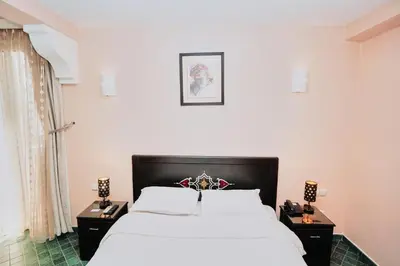 a bedroom with a large bed and two night stands at Hôtel Texuda in Rabat
