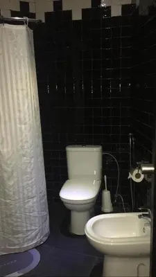 a bathroom with a toilet and a shower curtain at Hôtel Texuda in Rabat