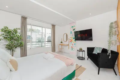 a white bedroom with a bed and a chair at Stayhere Rabat - Agdal 1 - Comfort Residence in Rabat