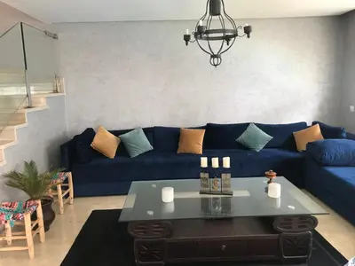 a living room with a blue couch and a table at Chez Didier Tamaris Beach in Dar Bouazza
