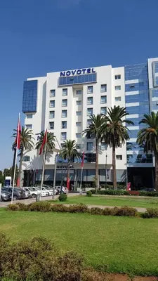 a hotel with palm trees in front of a building at Du Haut Standing au coeur du Parc et Plage à 180 m in Mohammedia