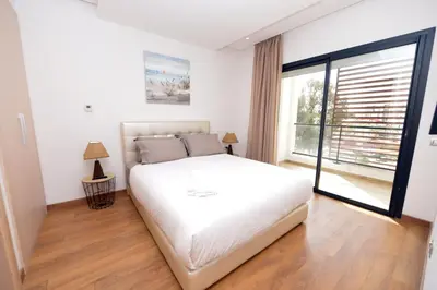 a bedroom with a white bed and a large window at Prestigia Rabat Hay Riad Premium Apartments in Rabat