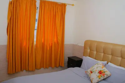 a bedroom with a bed and orange curtains at Bouznika 22 in Bouznika
