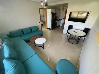 a living room with a blue couch and a table at CASA BEACH HOTEL in Sidi Rahal