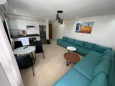 a living room with a blue couch and a kitchen at CASA BEACH HOTEL in Sidi Rahal