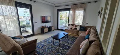 a living room with a couch and a tv at Appartement neuf haut standing vue mer in Skhirat