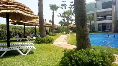 a resort with a pool and some chairs and umbrellas at Appartement au Bord de la Mer in Casablanca