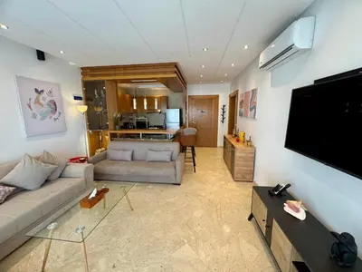 a living room with a couch and a flat screen tv at Peninsula Dar Bouazza Superbe appartement en résidence avec piscine activités in Dar Bouazza