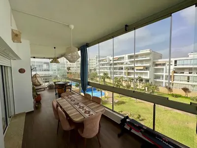 a living room with a large window with a view of a building at Peninsula Dar Bouazza Superbe appartement en résidence avec piscine activités in Dar Bouazza