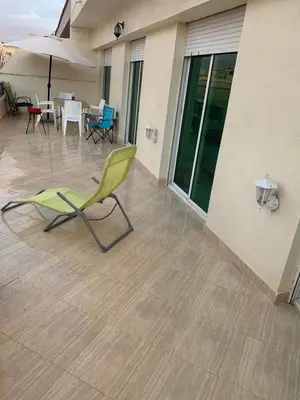 a green chair on a patio with a table at A 5 minutes à pied de la plage un bel appartement à saisir in Sidi Rahal