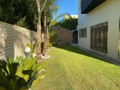 a yard with palm trees next to a house at Lilas Park Villa - Casablanca Bouskoura in Casablanca