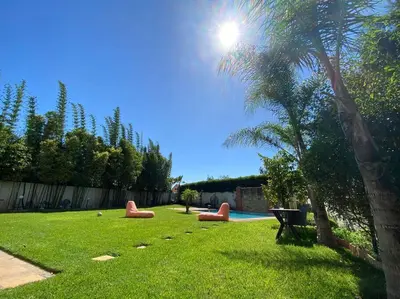 a yard with a pool with red furniture and a palm tree at Lilas Park Villa - Casablanca Bouskoura in Casablanca
