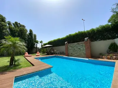 a swimming pool in a backyard with a wooden deck at Lilas Park Villa - Casablanca Bouskoura in Casablanca