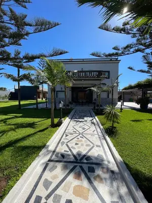 a walkway in front of a building with trees at Villa Safaa Dar Bouazza in Dar Mouddene