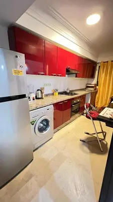 a kitchen with red cabinets and a white refrigerator at Studio de luxe in Casablanca