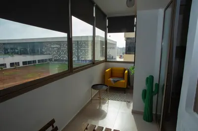 a room with a yellow chair and a large window at My Cosy Place Rabat - Appartements à 50m de la gare Agdal TGV in Rabat