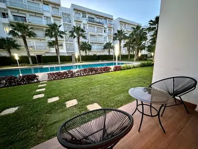 a patio with two chairs and a table and a yard at Apparemment de luxe vue piscine in Bouznika