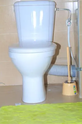 a white toilet in a bathroom with a brush at Appartement au centre ville in Bouznika
