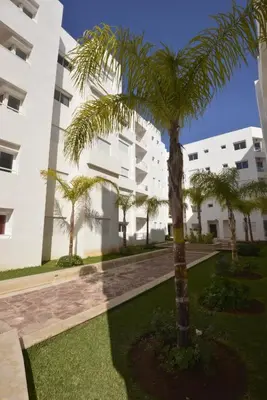 a palm tree in front of a building at BOUZNIKA Appartement avec piscine et plage à 3km in Bouznika