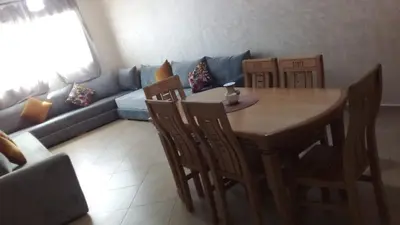 a living room with a table and chairs and a couch at BOUZNIKA Appartement avec piscine et plage à 3km in Bouznika