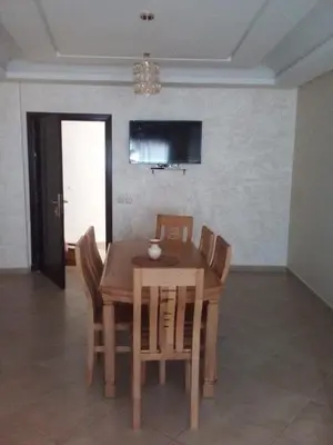 a wooden table and chairs in a living room at BOUZNIKA Appartement avec piscine et plage à 3km in Bouznika