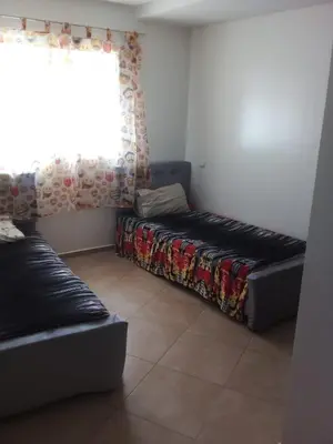 a bed in a room with a window and a couch at BOUZNIKA Appartement in Bouznika