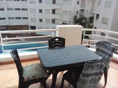a table and two chairs on a balcony with a pool at BOUZNIKA Appartement in Bouznika
