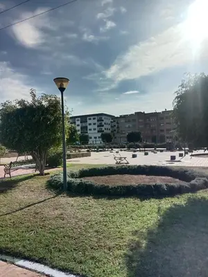 a light pole in a park with buildings in the background at Superbe appartement Bouznika in Bouznika
