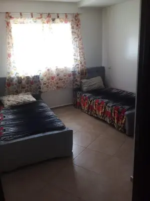 a living room with two beds and a window at Superbe appartement Bouznika in Bouznika