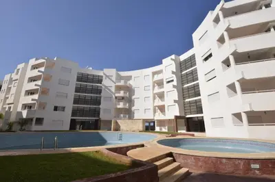 an apartment complex with a swimming pool in front of a building at Au Cœur de la ville de Bouznika in Bouznika