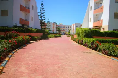 a red brick walkway between two buildings with flowers at La résidence des vagues in Mohammedia