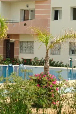 a house with a palm tree and flowers in front of it at La Perle de la Côte Atlantique in Mohammedia