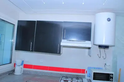 a kitchen with black and white cabinets and a microwave at BOUZNIKA T2 in Bouznika