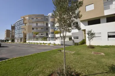 a tree in the grass in front of a building at BOUZNIKA T2 in Bouznika