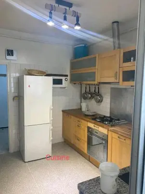 a kitchen with a white refrigerator and wooden cabinets at Appartement RIM in Casablanca