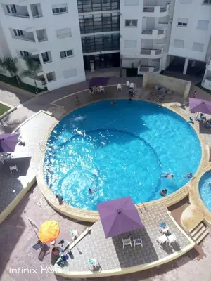 an overhead view of a large swimming pool with umbrellas at Le chant de la rivière BOUZNIKA in Bouznika