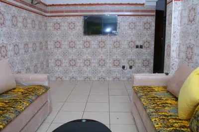 a room with a couch and a tv on a wall at Les temps heureux MOHAMMEDIA in Mohammedia