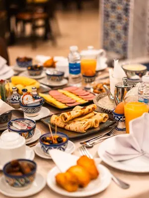 a table topped with plates of food and orange juice at Hotel Al Walid in Casablanca