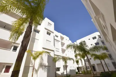 a white building with palm trees in front of it at Séjour à Bouznika in Bouznika