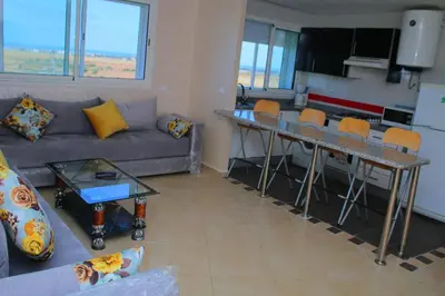 a living room with a couch and a table with chairs at BOUZNIKA CH1 98 in Bouznika