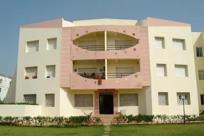 a pink building with a round balcony at MOHAMMEDIA Appartement avec 3 piscines et prés de plage in Mohammedia