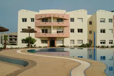 a building with a swimming pool in front of a building at Magnifique Appartement MOHAMMEDIA in Mohammedia