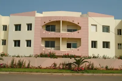 a pink building with flowers in front of it at Super Appartement MOHAMMEDIA in Mohammedia
