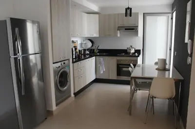 a kitchen with a stainless steel refrigerator and a table at MOHAMMEDIA piscine et plage in Mohammedia