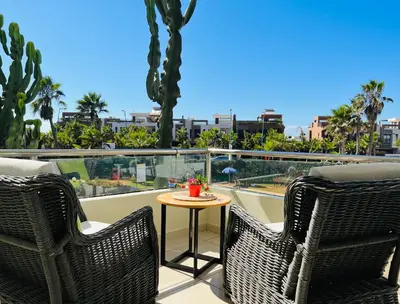 a balcony with two wicker chairs and a small table at Melrose Beαch Aρραrt Pοοl Vieω in Casablanca