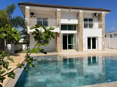 a villa with a swimming pool in front of a house at Skhirat VILLA Zhor in Skhirat